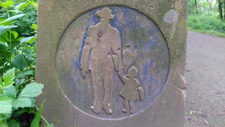 Eine in Stein gemeißelte Silhouette eines Mannes der ein Kind an der Hand hält, sie spazieren gemeinsam.