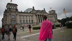Eine Frau mit einem pinken Tuch um die Schultern steht vor dem Deutschen Bundestag.