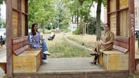 Zwei Frauen sitzen unter einer Holz-Pergola