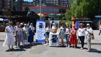 In a large public square on a bright, sunny day, staff members from Medica Zenica have lined up either side of their information stall to pose for a group photo.