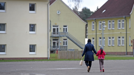 Eine Frau und ein Kind laufen auf einen Gebäudekomplex zu. 