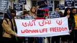 Frauen halten ein Transparent in den Händen mit den Worten „Frauen. Leben. Freiheit“ auf persisch und englisch.