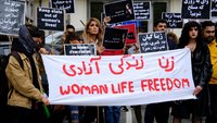 Frauen halten ein Transparent in den Händen mit den Worten „Frauen. Leben. Freiheit“ auf persisch und englisch.