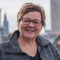 Eine Frau in einer schwarz-weißen Jacke steht auf einer Dachterrasse mit Kölner Dom im Hintergrund. Es ist Elke Ebert, Geschäftsführender Vorstand bei medica mondiale.