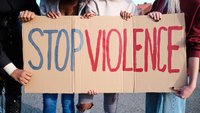 Ein Plakat, das von Frauen gehalten wird mit der Aufschrift "Stop Violence"