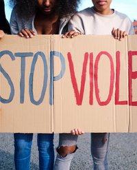 Ein Plakat, das von Frauen gehalten wird mit der Aufschrift "Stop Violence"