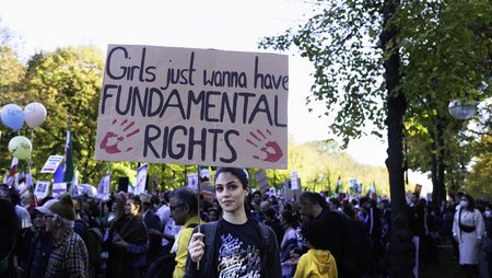 A woman is holding a sign with "Girls just wanna have fundamental rights" at a demonstration in solidarity.