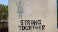 Ein Wandbild zeigt den Text "Strong together" - zusammen stark.