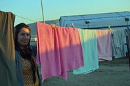 A resident of a refugee camp hanging up laundry