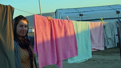 Eine Bewohnerin eines Geflüchtetenlagers beim Aufhängen von Wäsche