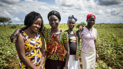 Mitarbeiterin der Partnerorganisation MEMPROW mit drei jungen Müttern auf einem gemeinschaftlich bearbeiteten Gemüsefeld. 