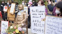 Trostfrauen-Statue in Berlin, ringsherum Menschen mit Demo-Plakaten