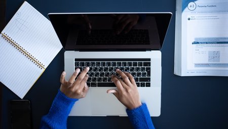 Photo of a pair of hands typing on a laptop.
