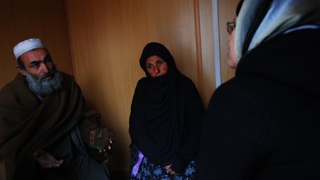 A man and a woman talking to a staff member from our Afghan partner organisation.