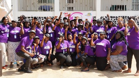 Group photo of staff members of different women's organisations, all wearing a purple T-shirt. 