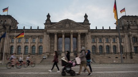 Some women pushing a pram past the German parliament building.