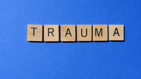 Wooden letter tiles taken from a game of Scrabble are arranged to form the word “trauma”.
