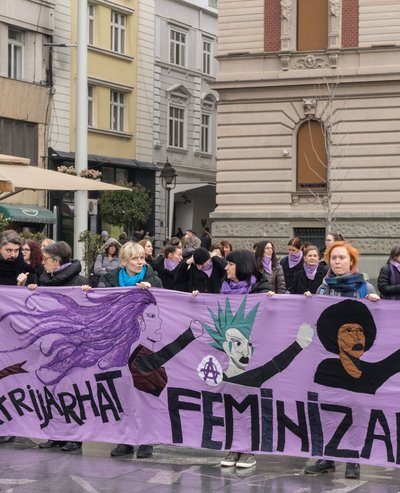 Frauen von Women in Black halten ein lila-farbenes feministisches Plakat bei einer Demonstration in Belgrad (Serbien).