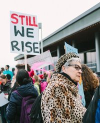 Women demonstrate for women's rights. A poster proclaims: "Still we rise".