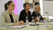 Three women are sitting at a conference table with microphones. They are Jeta Krasniqi on the left and Mirlinda Sada from Medica Gjakova on the right; in the middle Monika Hauser from medica mondiale, Cologne. 