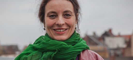 Eine Frau mit einem grünem Schal steht auf einer Dachterrasse mit Kölner Dom im Hintergrund. Es ist Sybille Fezer, Geschäftsführender Vorstand Internationale Programme bei medica mondiale.