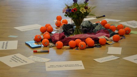 Foto von Utensilien einer Fortbildung: Anti-Stressbälle, Notizen eines Brainstormings, in der Mitte ein Blumenstrauß. 