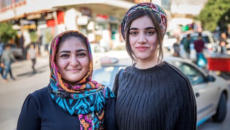 Portrait von zwei Frauen in Sulaymaniah im Nordirak, im Hintergrund eine belebte Straße. 