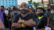 Staff from medica Liberia at a demonstration, with participants dressed in black. Black cloth covers their mouths and some are carrying candles.