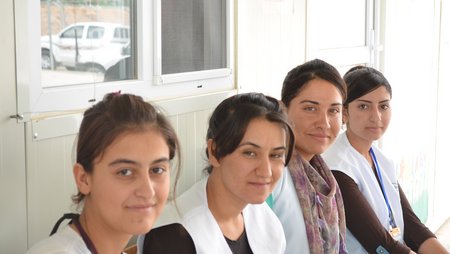 Four women in white lab coats smiling at the camera.