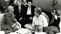 A group of women sit laughing around a table. It is the team of the Medica Zenica Women's Centre (photo in black and white, 1997). 