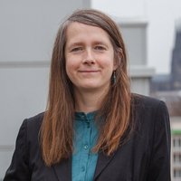 Eine Frau in einem schwarzen Blazer steht auf einer Dachterrasse mit Kölner Dom im Hintergrund. Es ist Sara Fremberg, Bereichsleitung Kommunikation und Politik bei medica mondiale.